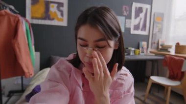 Gen Z kadın blogcusunun POV 'u burun bandajı çıkartıyor. Mücevherlerle süslenmiş, gülümsüyor ve yatak odasında kameraya poz veriyor. Aynı zamanda rinoplasti hakkında sosyal medya içeriği oluşturuyor.