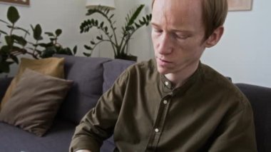 Kanepede otururken kör alfabesiyle kitap okuyan görme engelli bir adamın bakışını eğ.