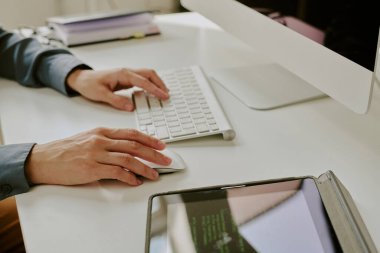 Bilgisayar klavyesinde yazı yazan ve modern ofiste kablosuz fare kullanan tanınmayan kadın bilişim uzmanlarının yakın çekimi.