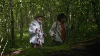 Ormanda yürürken yürüyüş çubukları kullanan çok ırklı çiftlerin görüntülerini izliyoruz.