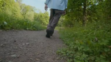 Ormanda yürürken çevresi yeşilliklerle çevrili iki kişinin her adımını izlediği el kamerasının düşük açılı görüntüsü