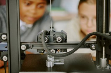 3 boyutlu karmaşık baskı sürecini gözlemleyen öğrenciler odaklanmış ifadelerle, eğitim ortamında teknolojiyi sergiliyorlar