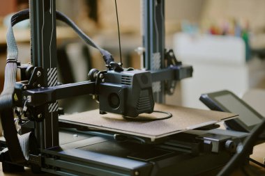 Bir atölye ayarı sırasında bir 3D yazıcıyı kapatarak arka planda görünen ve ekipmanı olan detaylı bileşenleri olan bir nesne oluşturur.
