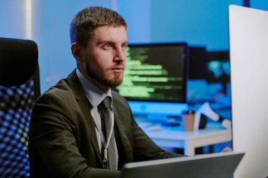 Masaüstü bilgisayar ekranı izleme siber güvenlik sistemine bakan genç Kafkas uzmanının orta boy görüntüsü.