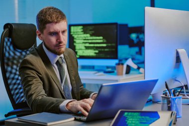 Modern bilişim şirketinin ofisindeki iş yerinde dizüstü bilgisayarda yazı yazan Kafkasyalı genç bir veri güvenlik uzmanı