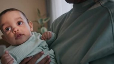 Afrika kökenli Amerikalı bir kadın onu öperken mutlu, genç annesinin ellerinde kameraya bakıp başını çeviren çok ırklı bir erkek bebek.