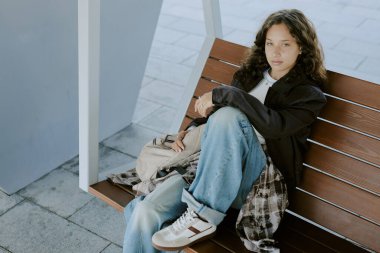 Parktaki ahşap bankta dinlenen genç kızın yüksek açılı portresi.