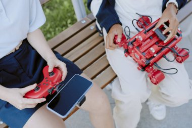 Yüksek açılı elektronik aletler, parktaki ahşap bankta oturan tanınmayan bir gencin ellerinde.