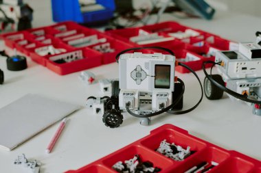 Orta ölçekli kare robot kısmı, silikon düğmeleri ve üzerinde kırmızı plastik kutular olan siyah kablolar.