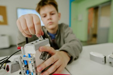 Robot bilimi dersi sırasında erkeklerin kabloyu robota bağladığı ortama yakın çekim.