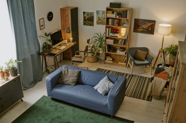 Yüksek açılı çalışma alanı, ahşap mobilyalar ve modern oturma odasındaki raflarda çok sayıda kitap.