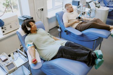 Farklı etnik geçmişlere sahip bireyler, gelişmiş tıbbi cihazlar ve ekipmanlarla profesyonel tıbbi ortamlara kan bağışlarken rahatça oturdular.