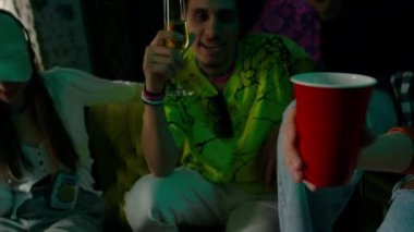 Genç adam, kız ve iki tanınmayan arkadaş partilerde kutlama yaparken içkilerini tokuşturuyorlar.