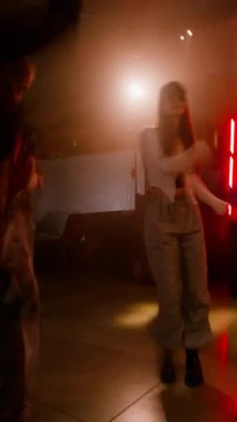 Dj 'in arka planda olduğu diskoda arkadaşlarıyla eğlenen enerjik gençlerin dikey çekimi.