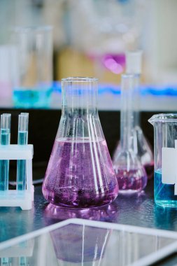 Bilimsel ortamda çeşitli renkli sıvılar sergileyen boş ve dolu bir laboratuvar bardağı.