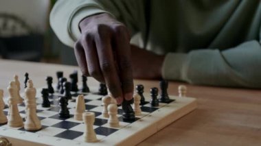 Satranç tahtasındaki şövalyeyi hareket ettiren ve oyun sırasında düşman kalesini ele geçiren tanınmamış siyahi adamın ellerine yakından bakın.
