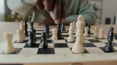 Evde tek başına satranç oynarken piyonu vezir ile birlikte yakalayan tanınmayan Afro-Amerikan adamın yakın çekimleri.