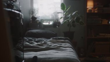 Yatak, kitap rafı, yer lambası, sandalye ve loş ışıkta dağınık ahşap masa olan küçük bir odanın içinde çekim yapmak yok.