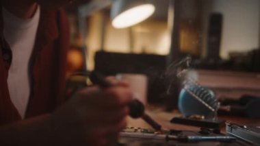 Yakın çekim, genç teknisyenin akıllı telefon lehimleme anakartını evde tamir ederken aşağı eğme görüntüsü.