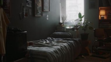 İnsanların mobilya ve kişisel eşyalarla dolu dağınık bir odanın içini görmesi yasak. Ahşap masa üzerindeki elektronik aletlerin bir kısmı loş ışık altında.