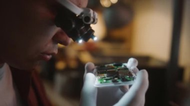 Erkek öğrencinin cep telefonuyla büyüteç takıp küçük detaylarını incelerken yakın plan görüntüsü.