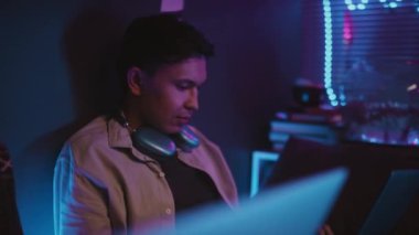 Z Geni programcısı dizüstü bilgisayarda kodluyor ve neon ışıklı odada bilinmeyen bir arkadaşıyla bira şişesini tıkırdatıyor.