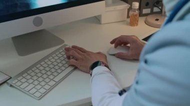 Kadın doktorun tesettüre girdiği yakın plan çekimde hastane çalışma saatleri boyunca bilgisayarındaki göğüs röntgenini analiz ederken.