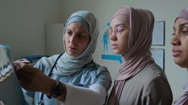 Müslüman anne-kız tesettürdeki kadın doktoru dinliyor. Tıp bürosunda onlara beyin MR 'ı anlatıyor.