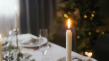 Evdeki Noel kutlaması için hazırlanmış şenlikli yemek masasının üzerindeki mum manzarasını kapat.