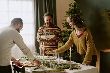 Beyaz tenli bir aile Noel partisi hazırlıkları sırasında beyaz tabaklar ve aperatiflere lezzetli yemekler koyuyor.