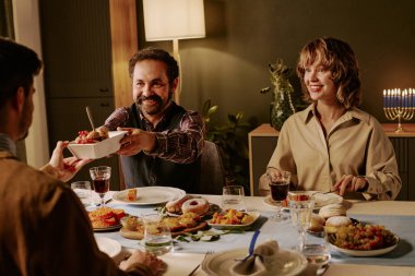 Farklı ikram ve yemekleri olan melez bir arkadaş grubu onları yiyor. Arkadaşına neşeli bir tabak dolusu fırında patates sunuyor.