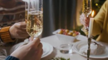 Arkadaşların elleri yemek masasında otururken, kadeh tokuştururken evde birlikte Noel 'i kutlarken.