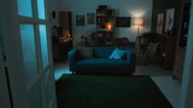 Kimse yeşil halısı, mavi koltuğu, dolabı, kitaplığı, masası ve loş ışıktaki diğer mobilyaları olan modern oturma odasının içini büyütmüyor.