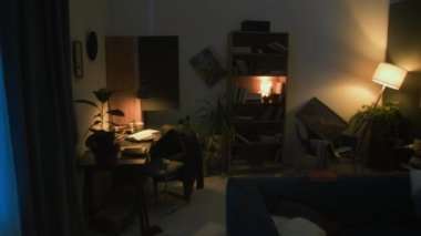 Kimse lambayla aydınlatılmış dağınık oturma odasına bakmaz. Dolabın kapısı açıktır. Düşen resimler vardır.