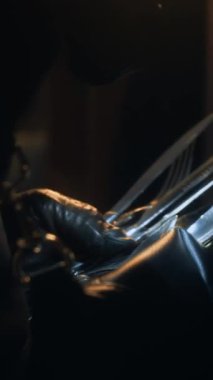 Daire soygunu sırasında gümüş çatal bıçak takımını el feneriyle aydınlatırken, tanınmayan bir suçlunun dikey yakın çekimi.