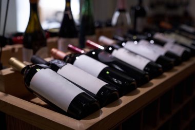 Sunum sırasında ahşap masada yıllanmış kırmızı şaraplı loş şişeleri orta derecede kapat.