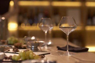 Masada beyaz şarapla cilalanmış kristal bardaklar, loş aydınlatılmış şarap mahzeninde şarap israfı için aperatiflerle servis edilir.