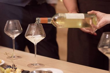 Zarif bir kadın eli soğuk beyaz şarabı aperatiflerle servis edilen masaların üzerine cilalanmış kristal bardağa dolduruyor.