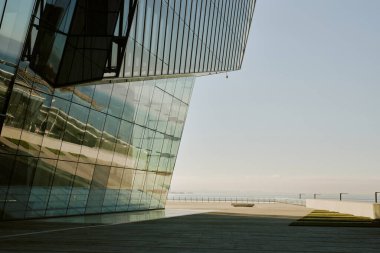 Modern cam bina deniz kıyısındaki çevreyi yansıtıyor. Açık gökyüzü ve boş gezinti alanı mimari tasarım elementleriyle tezat oluşturuyor