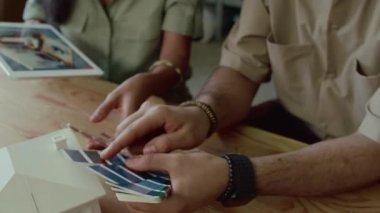 Çeşitli tasarımcıların, üzerinde oda modeli olan dijital tablet ekranına bakmalarını ve oturma odası için iç mekan yaratırken paletten renk seçmelerini sağla.