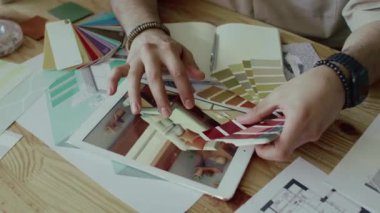 Renk paleti tutarken kameraya bakan Z jenerasyonunun erkek tasarımcısının portresini kaldır ve daire dekorasyonu için çözümler seç, dijital tablette iç mekanın 3D modeli