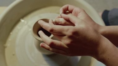 Kimliği belirsiz kadın zanaatkarın çömlekçi çarkında kil vazo yaparken yakın çekim görüntüsü.