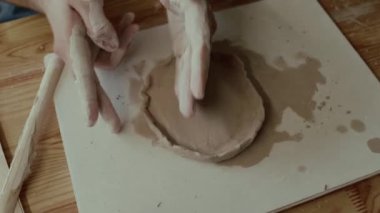 Ahşap masada kil döşeyen bilinmeyen erkek çömlekçinin yakın çekim görüntüsü.
