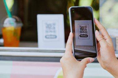 Menüyü okumak için QR kodunu tarayan tanınmayan bir kadının orta ölçekli görüntüsü