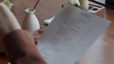 Menüyü tutarken, restoranda ne sipariş edileceğini seçerken, yemek isimlerine işaret eden, tanınmayan kişilerin yakın plan fotoğrafları.