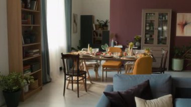 İnsanların oturma odasının içini göremeyeceği mobilyalar, yer bitkileri ve sandalyelerle çevrili tatil yemek masası ev kutlamaları için servis edilecek.