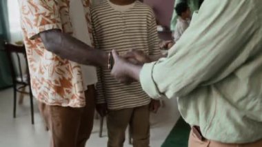 Pozitif kıdemli bir adamın oğlunu el sıkışarak selamlamasını, sonra torunlarını göstermesini ve kel kafasına dokunmasını.