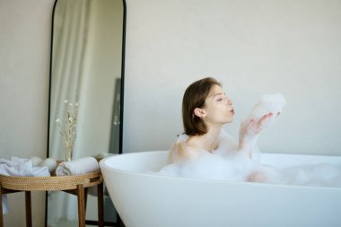 Kafkasyalı esmer kadın evde dinlenirken köpük üflüyor.