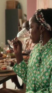 Aile toplantısında limonata içerken kameraya poz veren Afro-Amerikan kadının dikey portresi