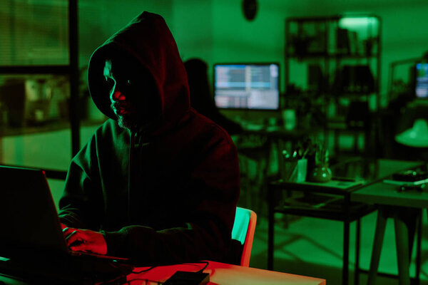Медиум крупным планом фото веб-преступника в комнате, подсвеченной зеленым цветом
